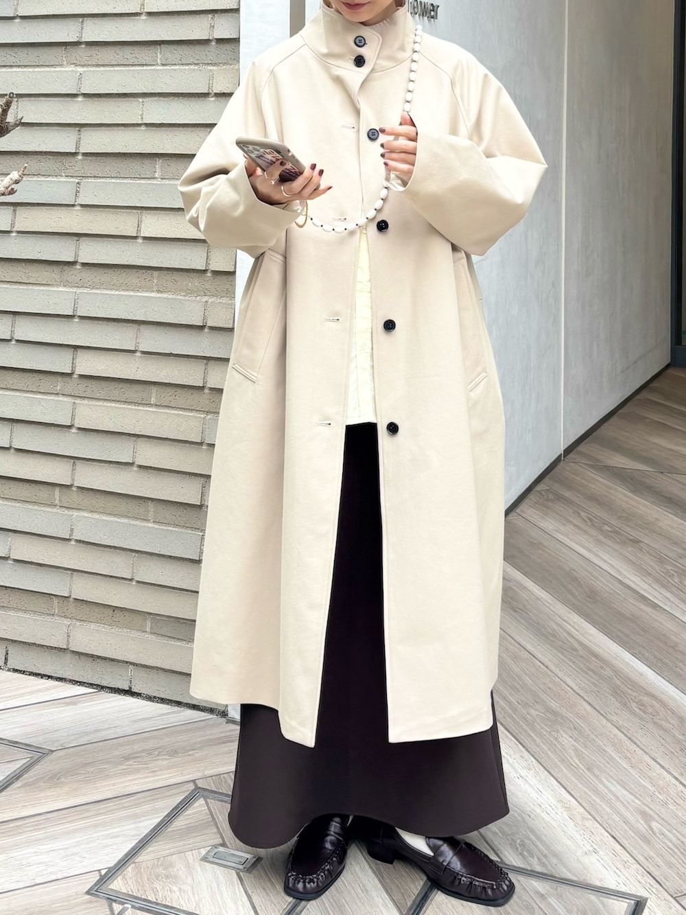 ブラウン系のローファー、ベージュ系のその他アウター、ブラウン系のスカートを着用したレディースの冬コーディネートの3枚目の写真