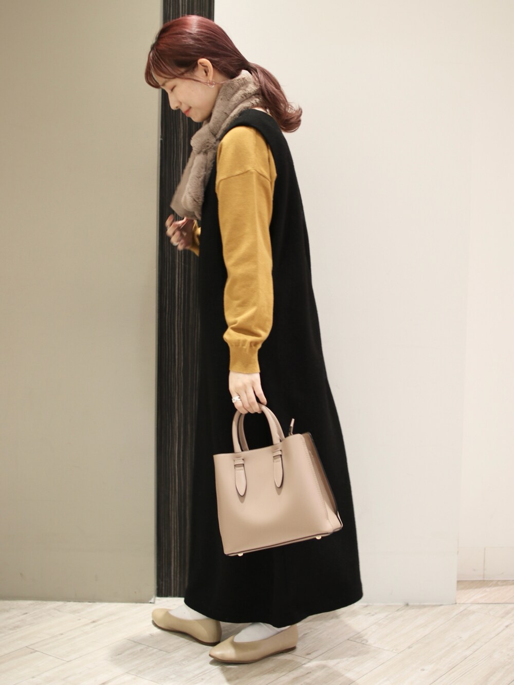ブラウン系のトートバッグ、ブラック系のワンピース、イエロー系のニット/セーターを着用したレディースの冬コーディネートの3枚目の写真