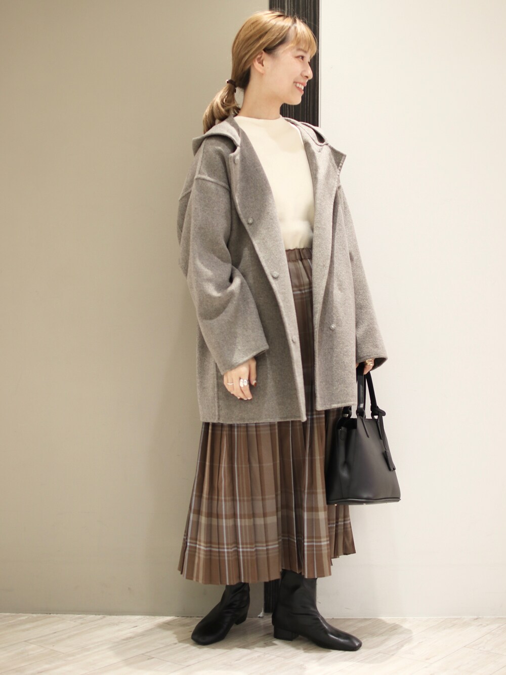ホワイト系のニット/セーター、グレー系のその他アウター、ブラック系のハンドバッグを着用したレディースの秋コーディネートの2枚目の写真