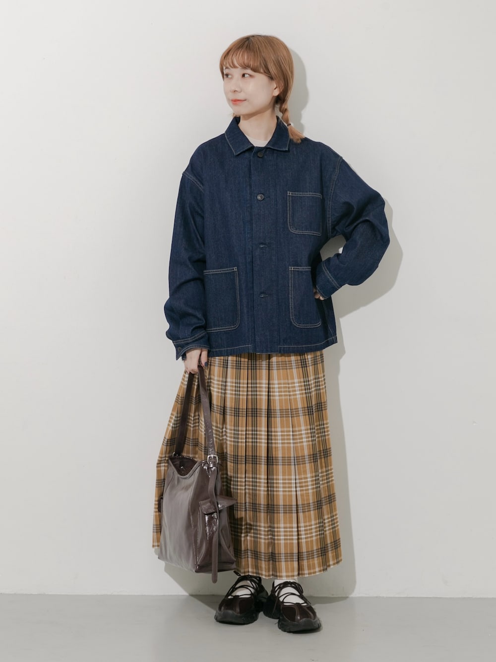 ブラウン系のスニーカー、ブルー系のカバーオール、イエロー系のスカートを着用したレディースの秋コーディネートの4枚目の写真