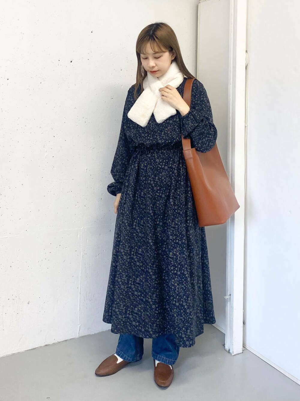 ブラウン系のスリッポン、ブルー系のデニムパンツ、ブラウン系のトートバッグを着用したレディースの秋コーディネートの4枚目の写真