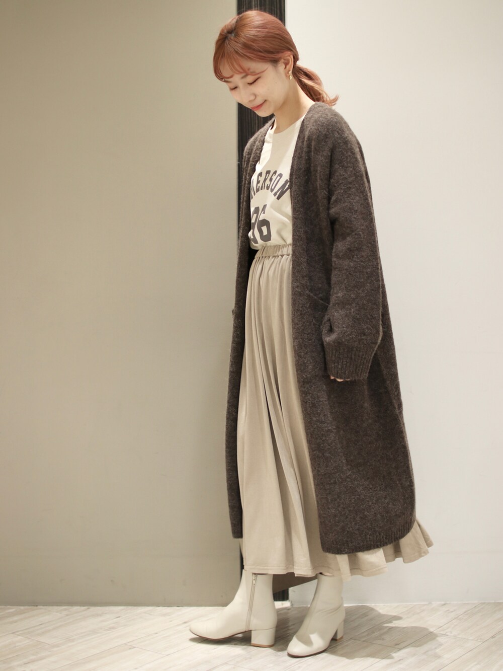 グレー系のスカート、ホワイト系のブーツ、グレー系のトートバッグを着用したレディースの秋コーディネートの3枚目の写真