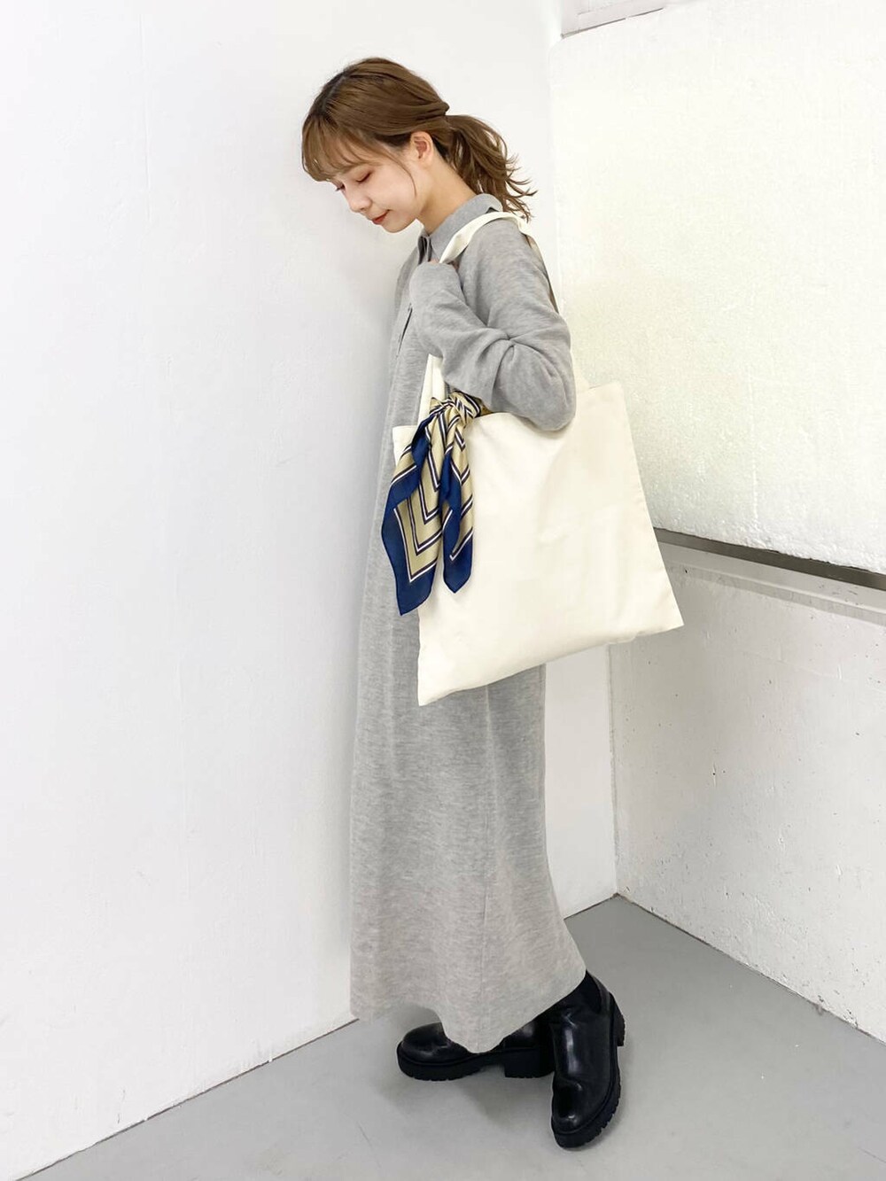 ブラック系のブーツ、ホワイト系のトートバッグ、グレー系のワンピースを着用したレディースの秋コーディネートの3枚目の写真