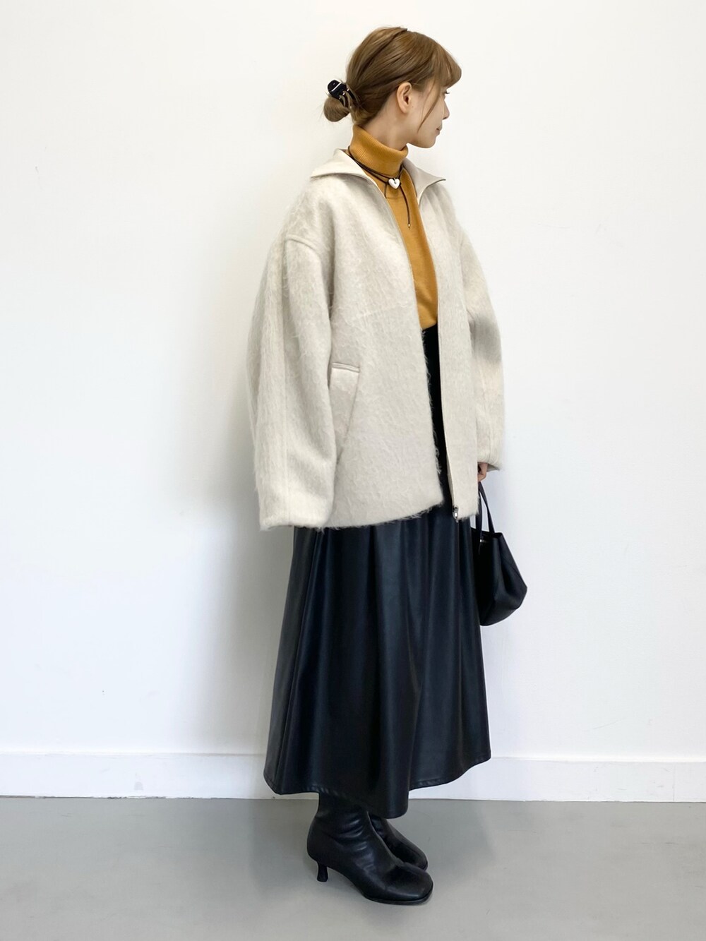 ブラック系のショルダーバッグ、ブラック系のブーツ、ブラック系のスカートを着用したレディースの冬コーディネートの2枚目の写真