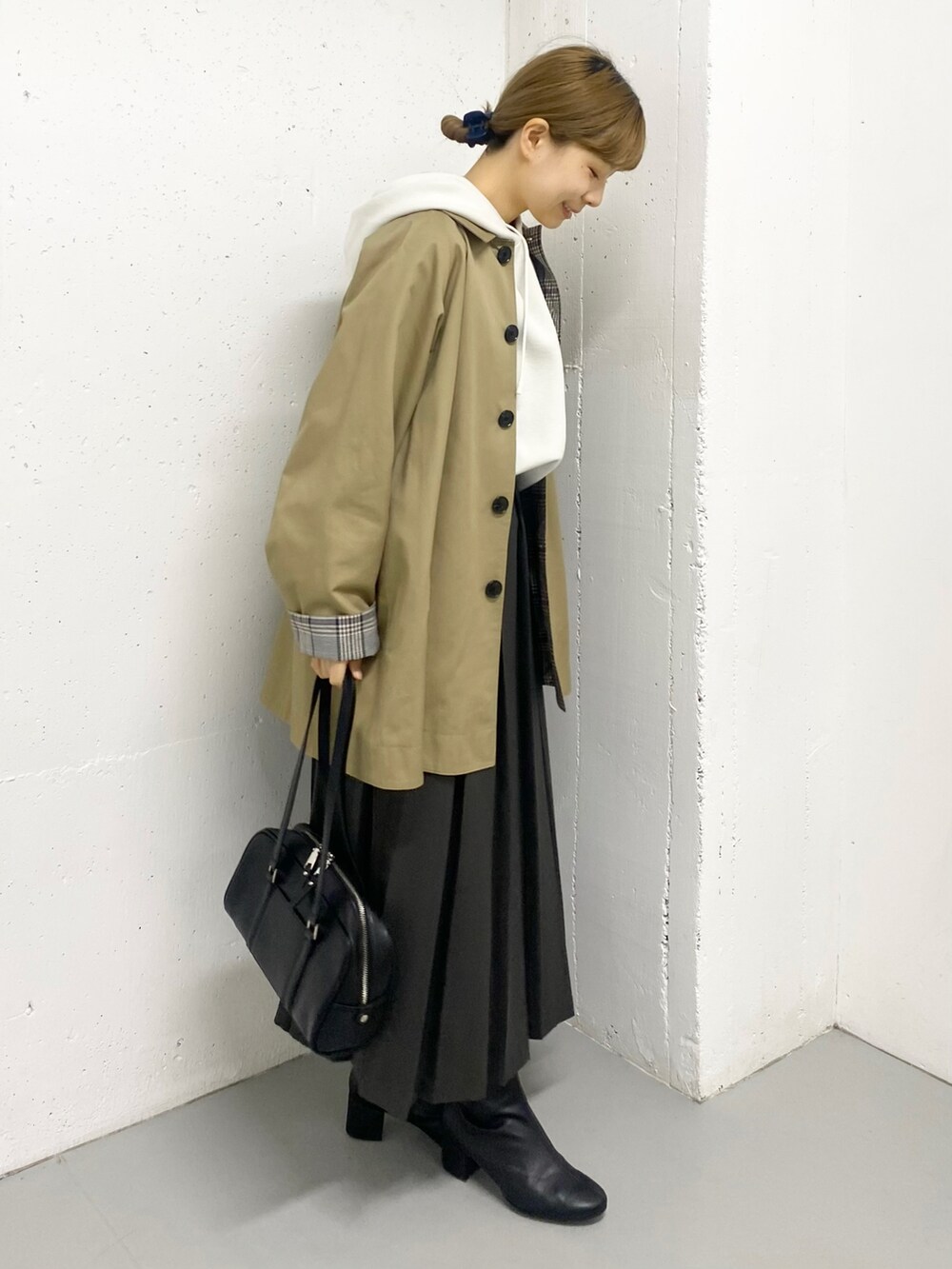 グレー系のスカート、ブラック系のブーツ、ベージュ系のステンカラーコートを着用したレディースの秋コーディネートの4枚目の写真