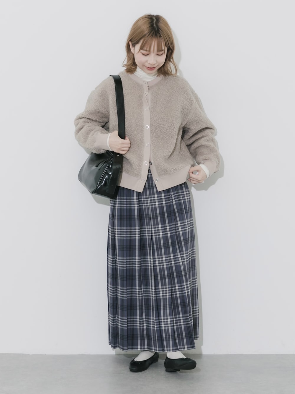 グレー系のスカート、ベージュ系のカーディガン/ボレロ、ブラック系のショルダーバッグを着用したレディースの秋コーディネートの2枚目の写真