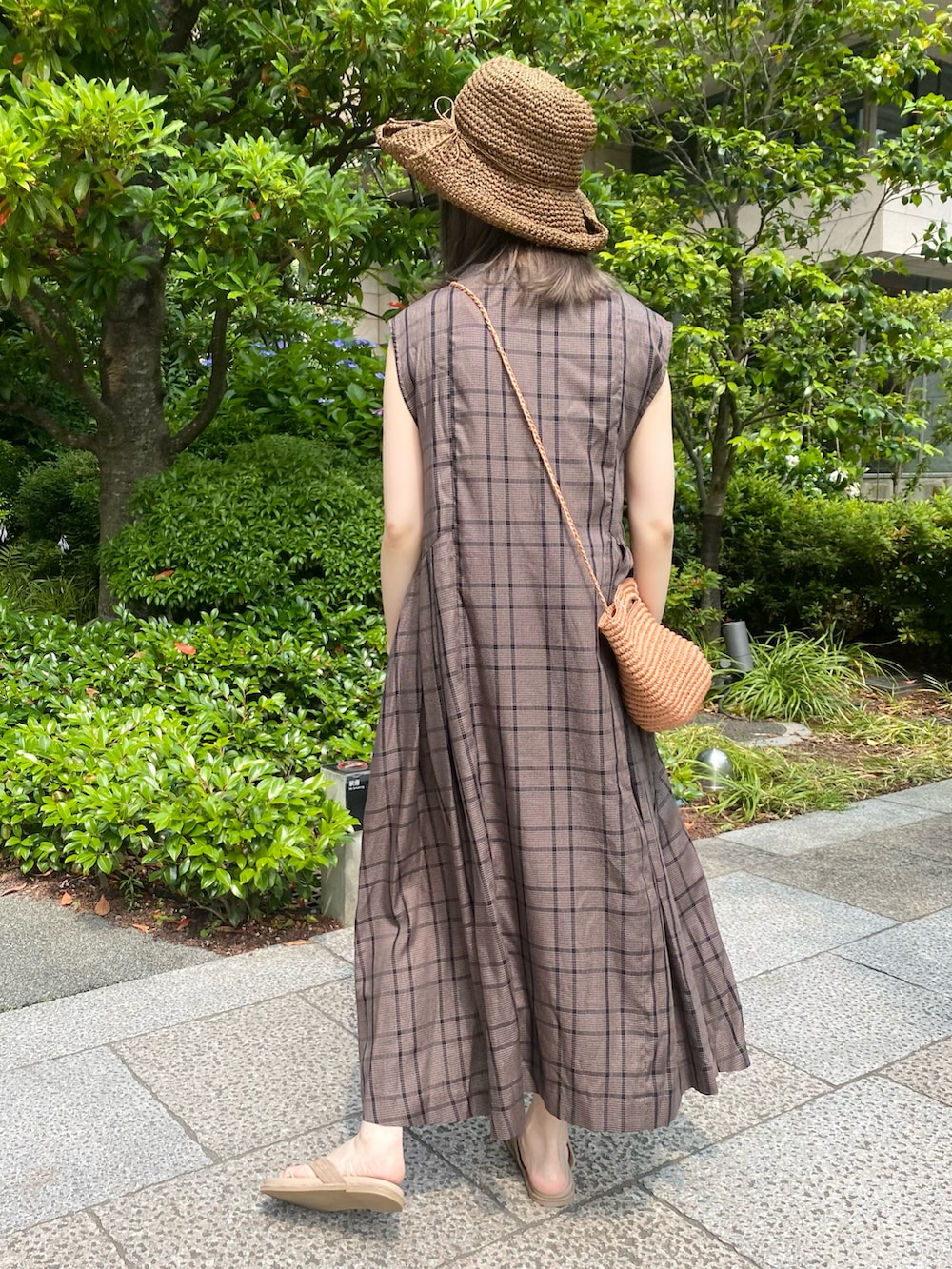 ベージュ系のかごバッグ、ブラウン系のワンピース、ベージュ系のサンダルを着用したレディースの夏コーディネートの2枚目の写真