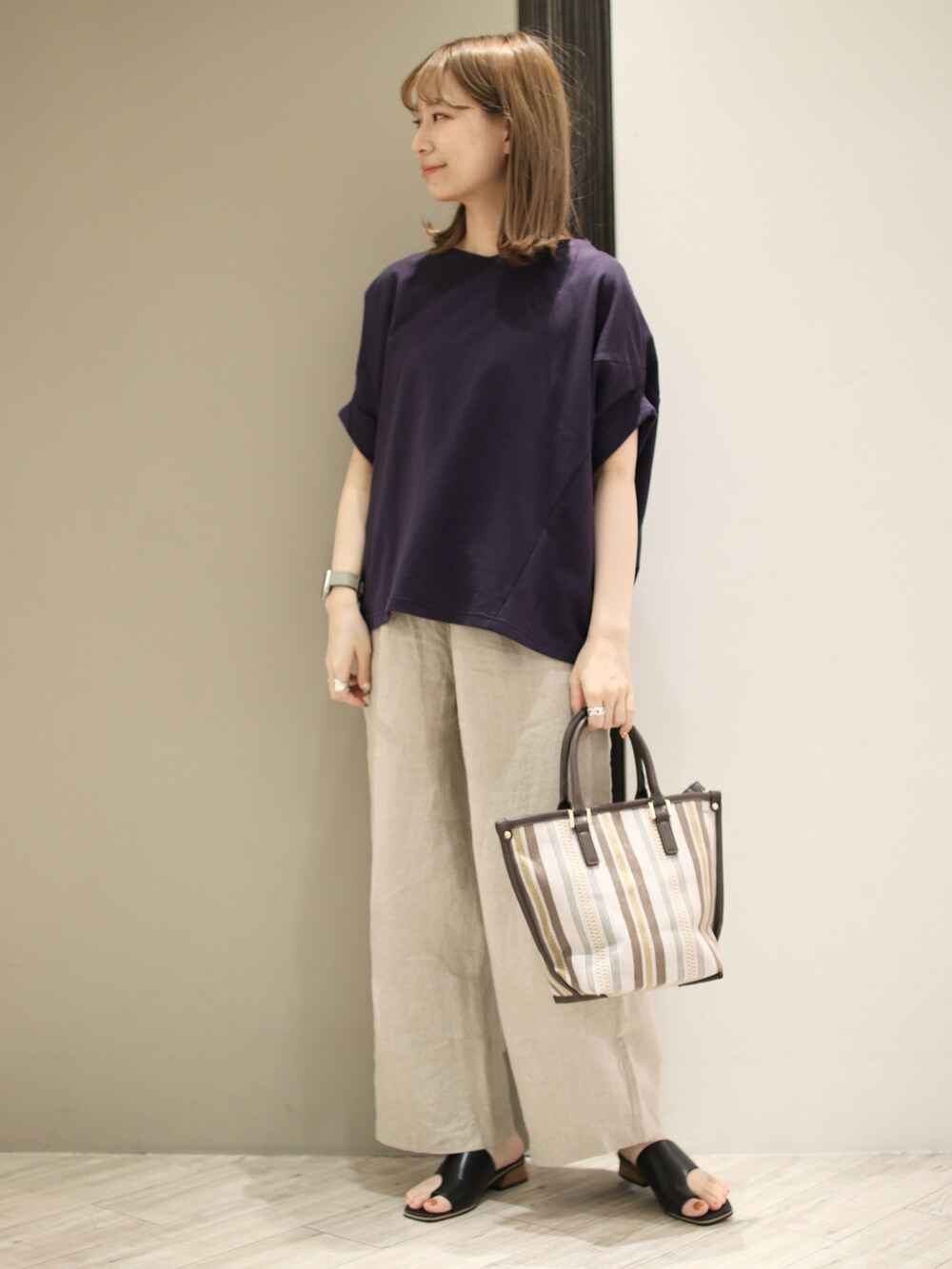 ブラウン系のトートバッグ、ベージュ系のその他パンツ、ブラック系のサンダルを着用したレディースの春コーディネートの2枚目の写真