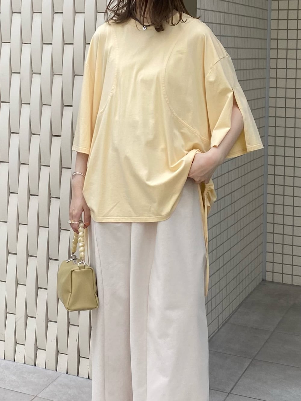 ブラウン系のサンダル、ベージュ系のショルダーバッグ、イエロー系のTシャツ/カットソーを着用したレディースの夏コーディネートの5枚目の写真