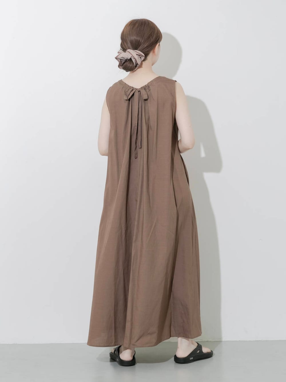 ブラック系のサンダル、ベージュ系のハンドバッグ、ゴールド系のネックレスを着用したレディースの夏コーディネートの3枚目の写真