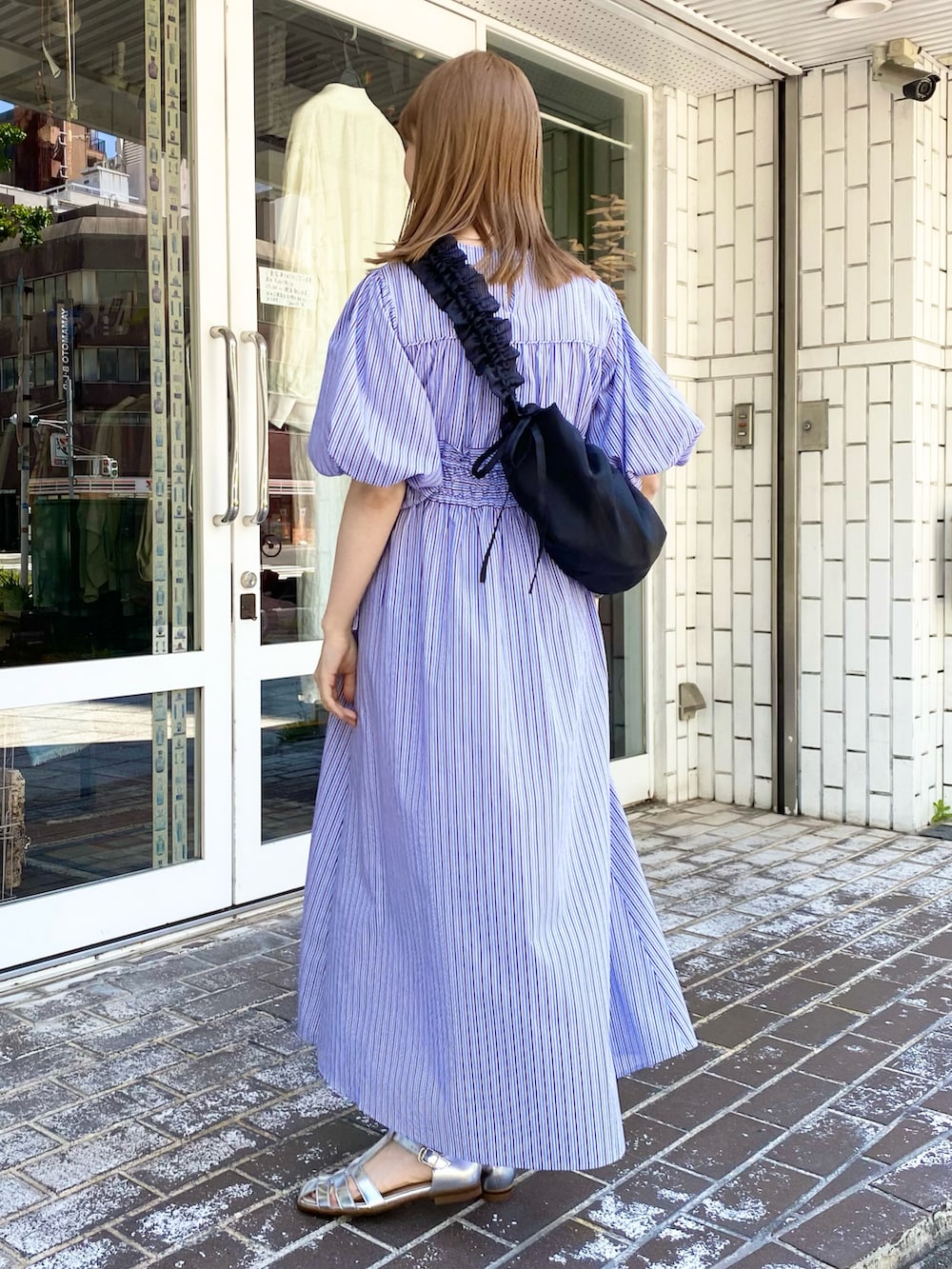 ブラック系のショルダーバッグ、パープル系のワンピース、シルバー系のサンダルを着用したレディースの夏コーディネートの2枚目の写真