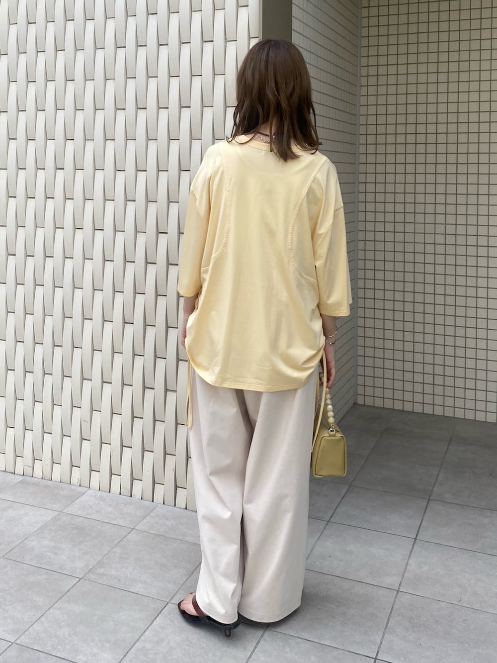 ブラウン系のサンダル、ベージュ系のショルダーバッグ、イエロー系のTシャツ/カットソーを着用したレディースの夏コーディネートの3枚目の写真