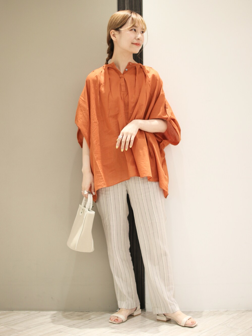 オレンジ系のシャツ/ブラウス、ベージュ系のその他パンツ、ベージュ系のショルダーバッグを着用したレディースの夏コーディネートの2枚目の写真