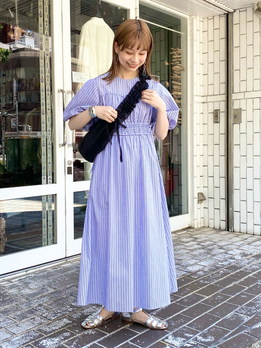 ブラック系のショルダーバッグ、パープル系のワンピース、シルバー系のサンダルを着用したレディースの夏コーディネートの3枚目の写真