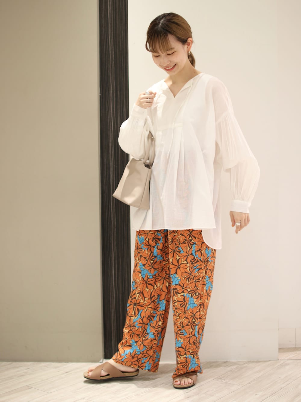 オレンジ系のその他パンツ、ホワイト系のシャツ/ブラウス、ベージュ系のハンドバッグを着用したレディースの夏コーディネートの2枚目の写真