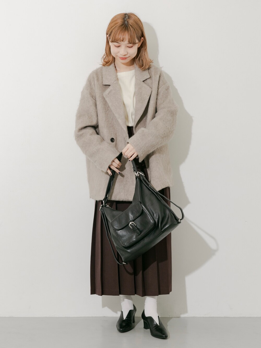 ブラウン系のスカート、ブラウン系のその他アウター、ホワイト系のTシャツ/カットソーを着用したレディースの秋コーディネートの8枚目の写真