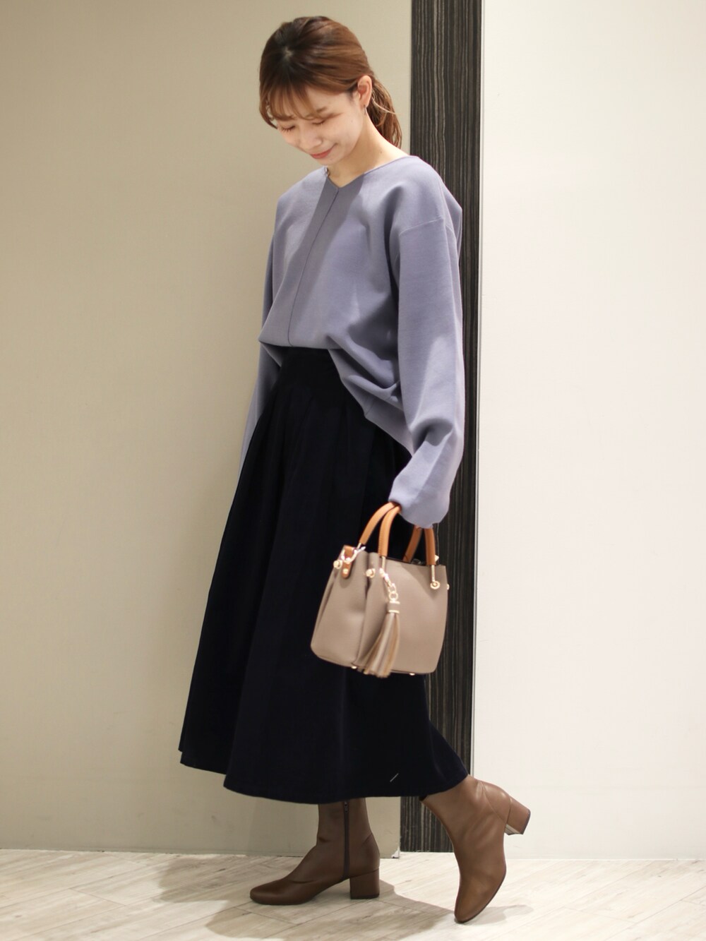 ベージュ系のトートバッグ、ブルー系のスカート、ブルー系のニット/セーターを着用したレディースの秋コーディネートの4枚目の写真