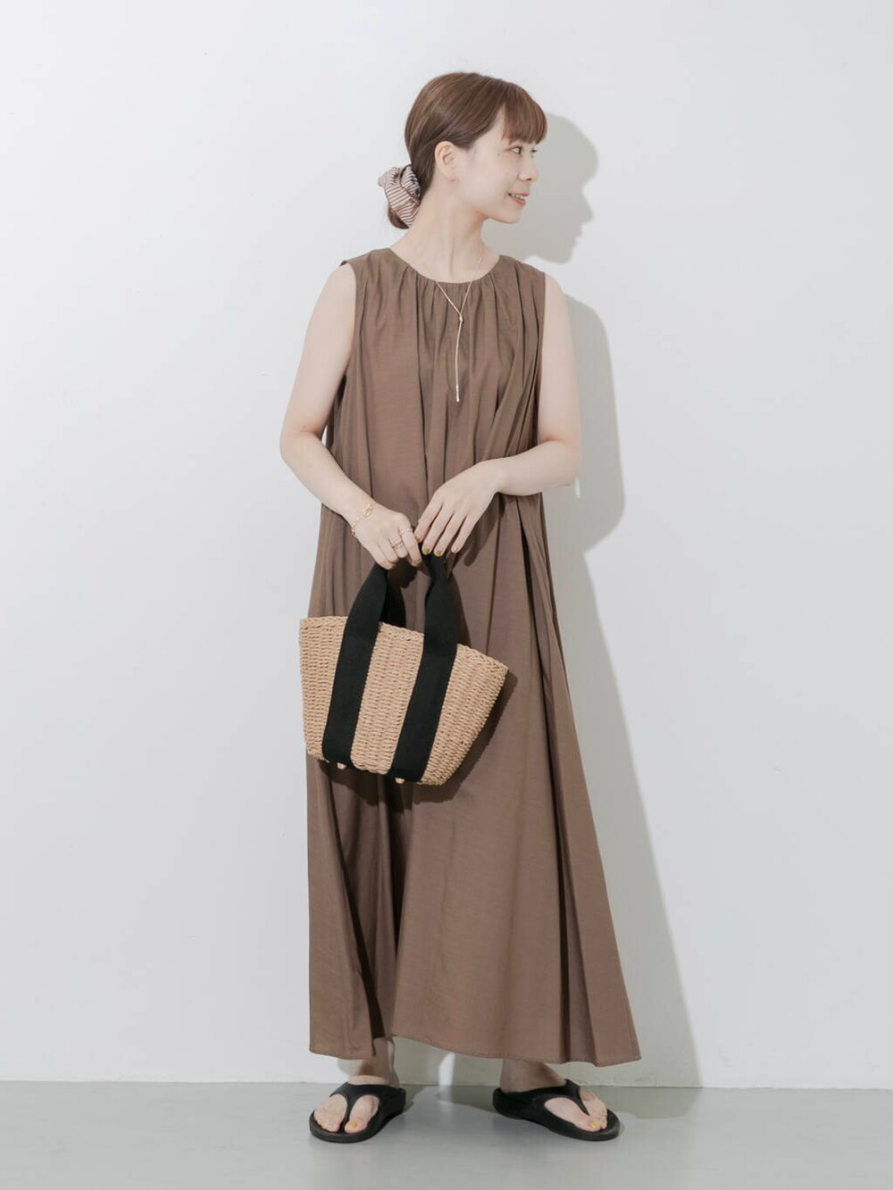 ブラック系のサンダル、ベージュ系のハンドバッグ、ゴールド系のネックレスを着用したレディースの夏コーディネートの7枚目の写真