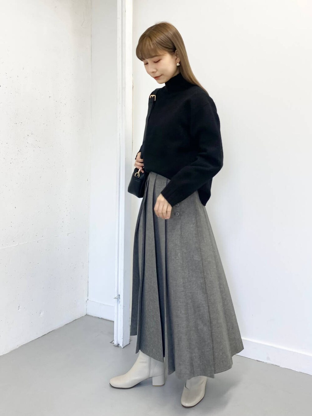 ホワイト系のブーツ、ブラック系のショルダーバッグ、グレー系のスカートを着用したレディースの冬コーディネートの2枚目の写真