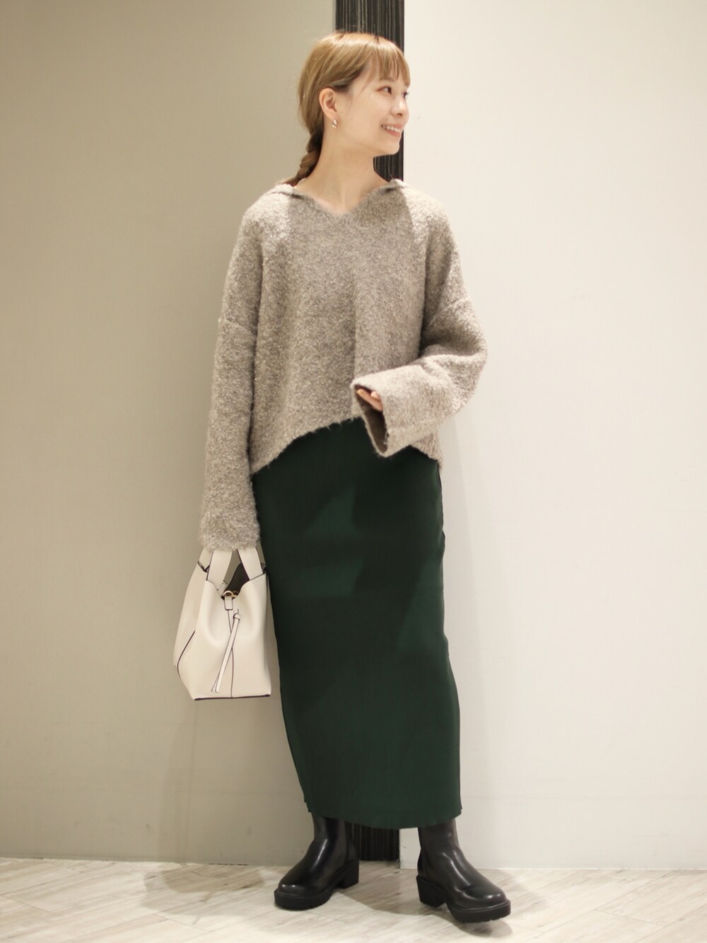 ホワイト系のトートバッグ、ブラック系のブーツ、グリーン系のスカートを着用したレディースの秋コーディネートの2枚目の写真