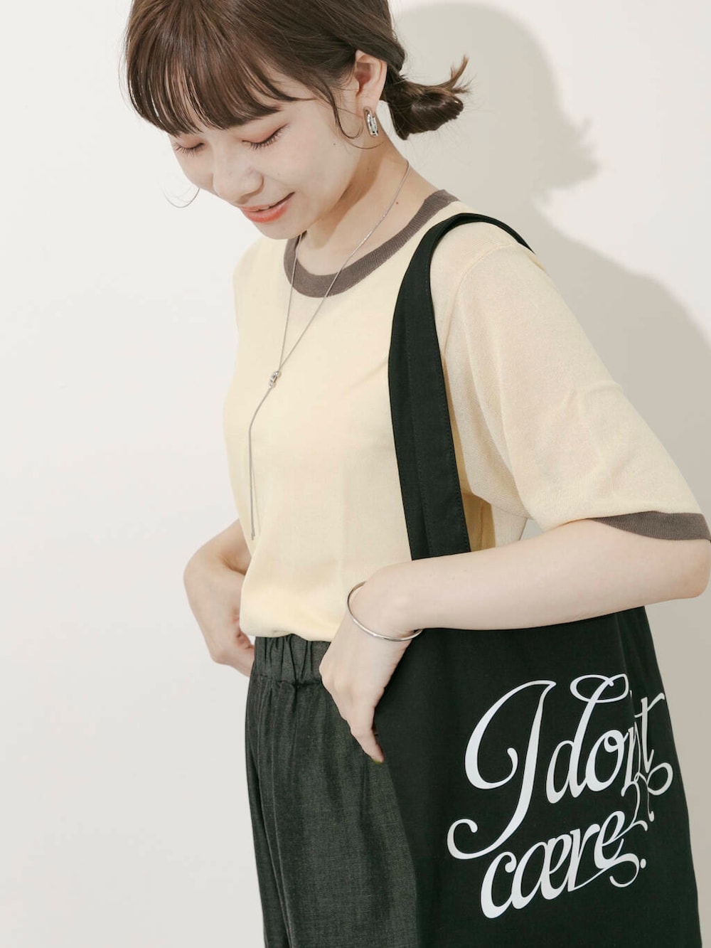 ブラック系のトートバッグ、ベージュ系のニット/セーター、ホワイト系のサンダルを着用したレディースの夏コーディネートの5枚目の写真