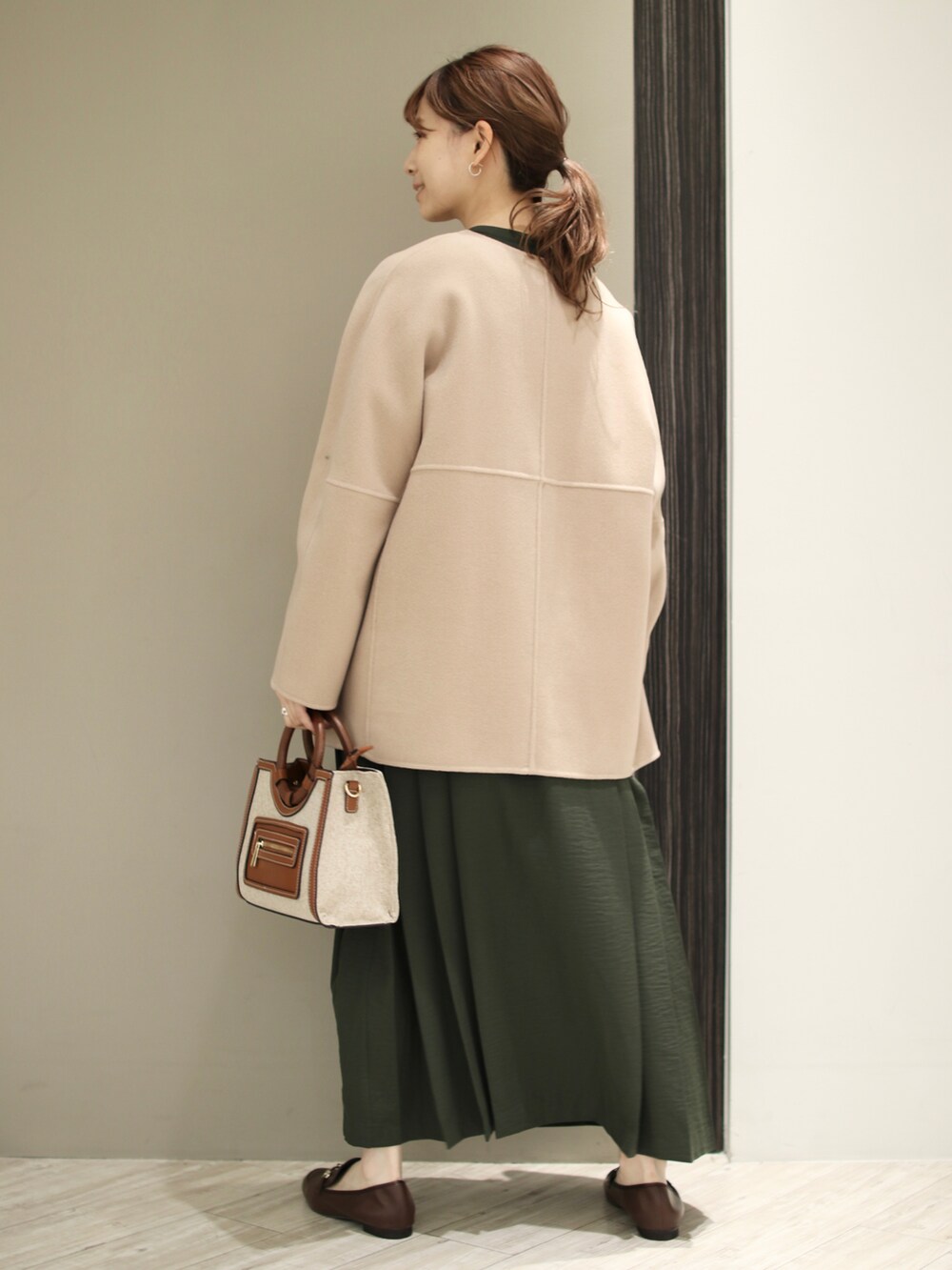 ブラウン系のトートバッグ、ブラウン系のローファー、グリーン系のワンピースを着用したレディースの秋コーディネートの4枚目の写真