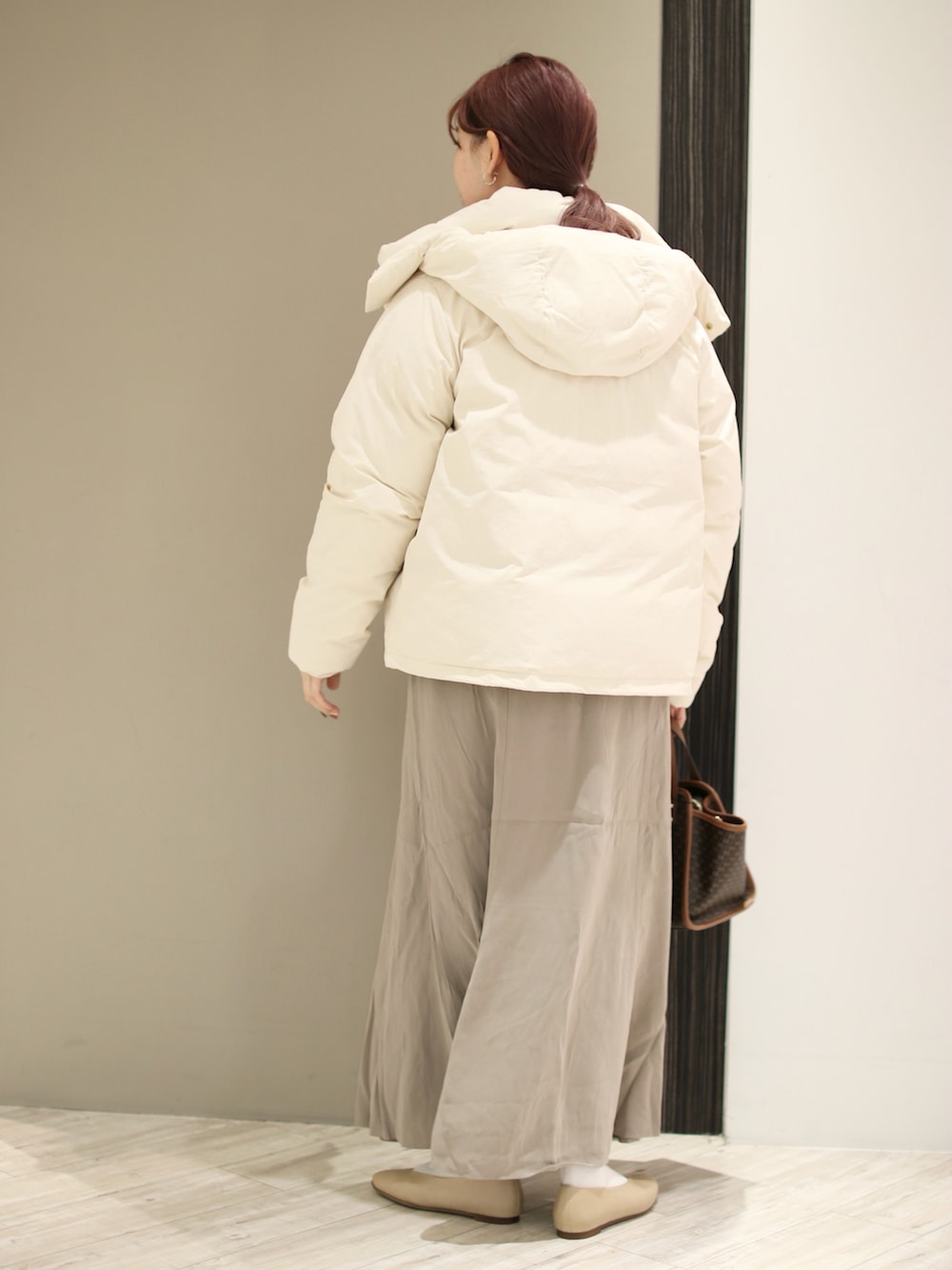 ホワイト系のダウンジャケット/コート、オレンジ系のニット/セーター、ベージュ系のスカートを着用したレディースの冬コーディネートの3枚目の写真