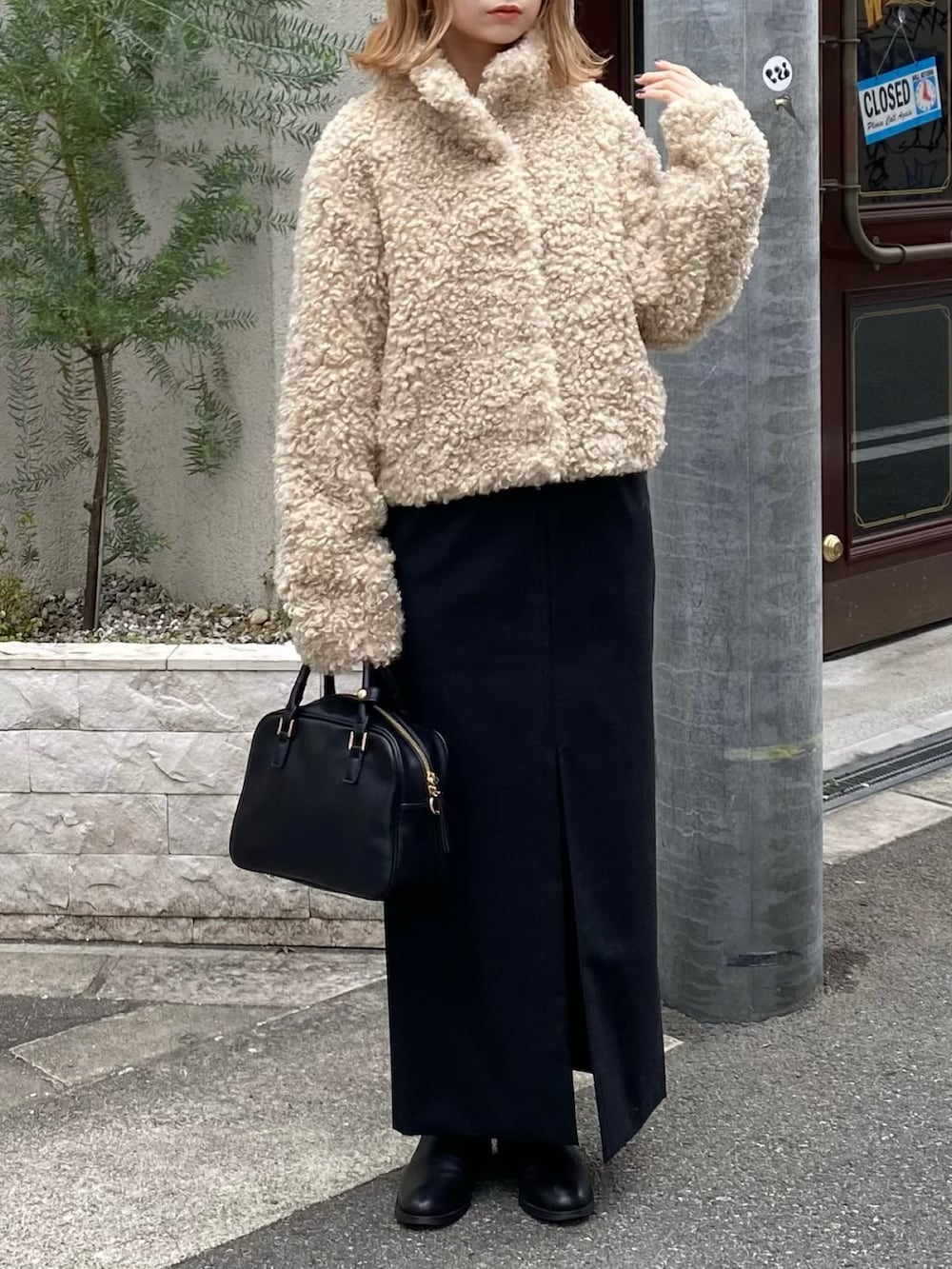 ホワイト系のその他アウター、ブラック系のスカート、ブラック系のボストンバッグを着用したレディースの冬コーディネートの4枚目の写真
