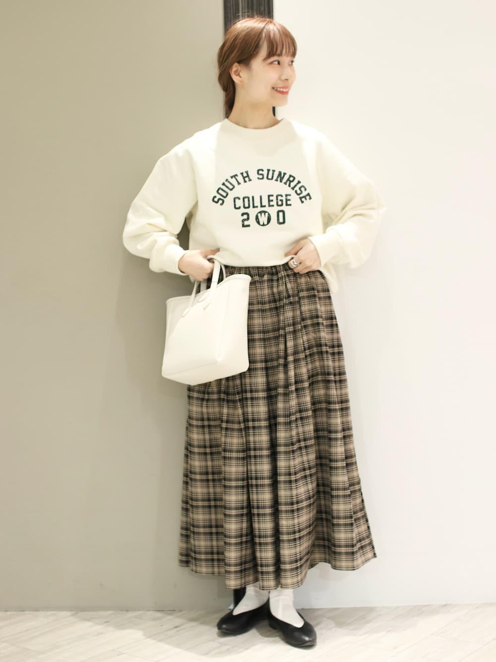 ベージュ系のスカート、ホワイト系のスウェット、ブラック系のパンプスを着用したレディースの冬コーディネートの2枚目の写真