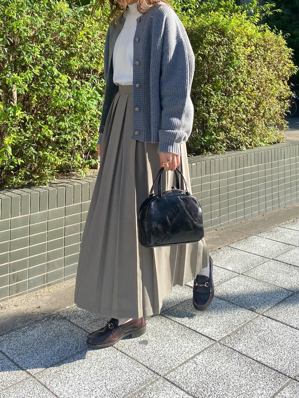 ブラウン系のローファー、ブラック系のショルダーバッグ、グリーン系のスカートを着用したレディースの秋コーディネートの2枚目の写真