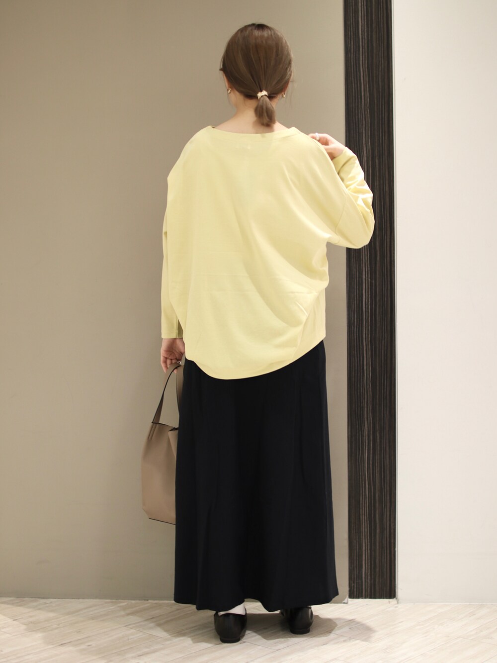 ベージュ系のトートバッグ、イエロー系のTシャツ/カットソー、ブルー系のスカートを着用したレディースの冬コーディネートの4枚目の写真