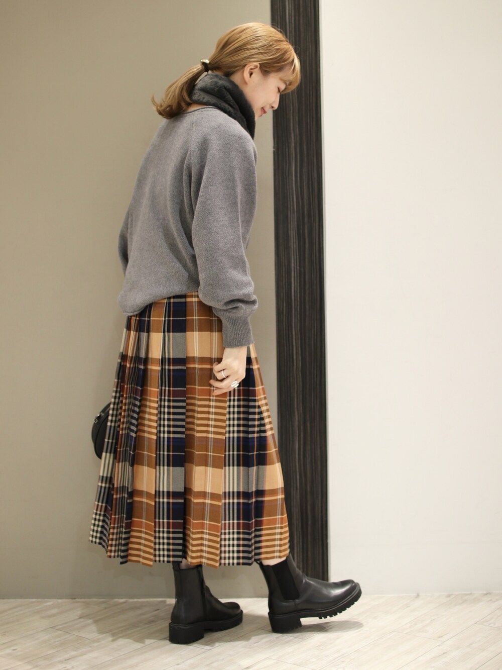 グレー系のニット/セーター、オレンジ系のスカート、ブラック系のショルダーバッグを着用したレディースの秋コーディネートの4枚目の写真