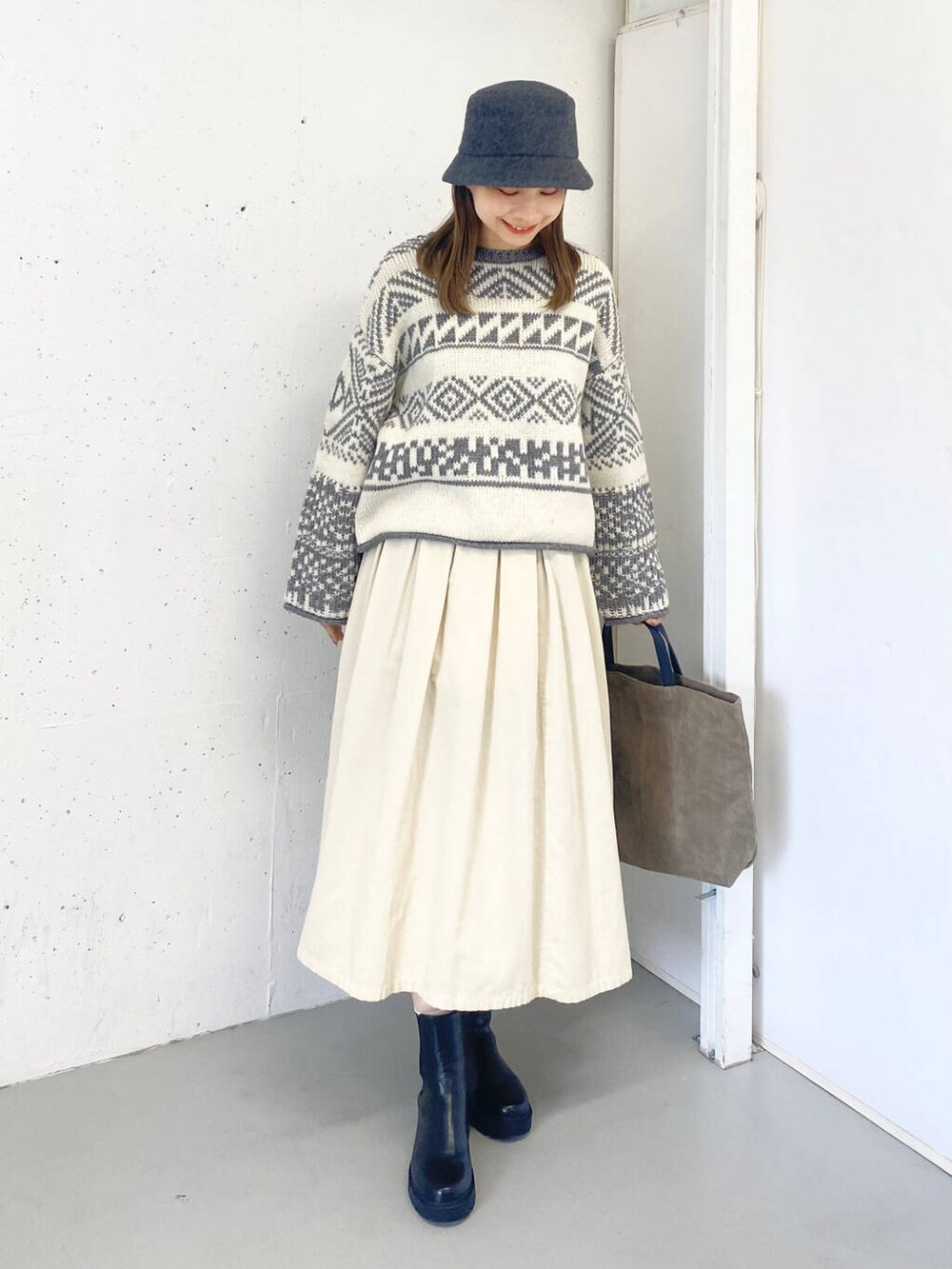 ベージュ系のトートバッグ、ブラック系のブーツ、ホワイト系のスカートを着用したレディースの秋コーディネートの5枚目の写真