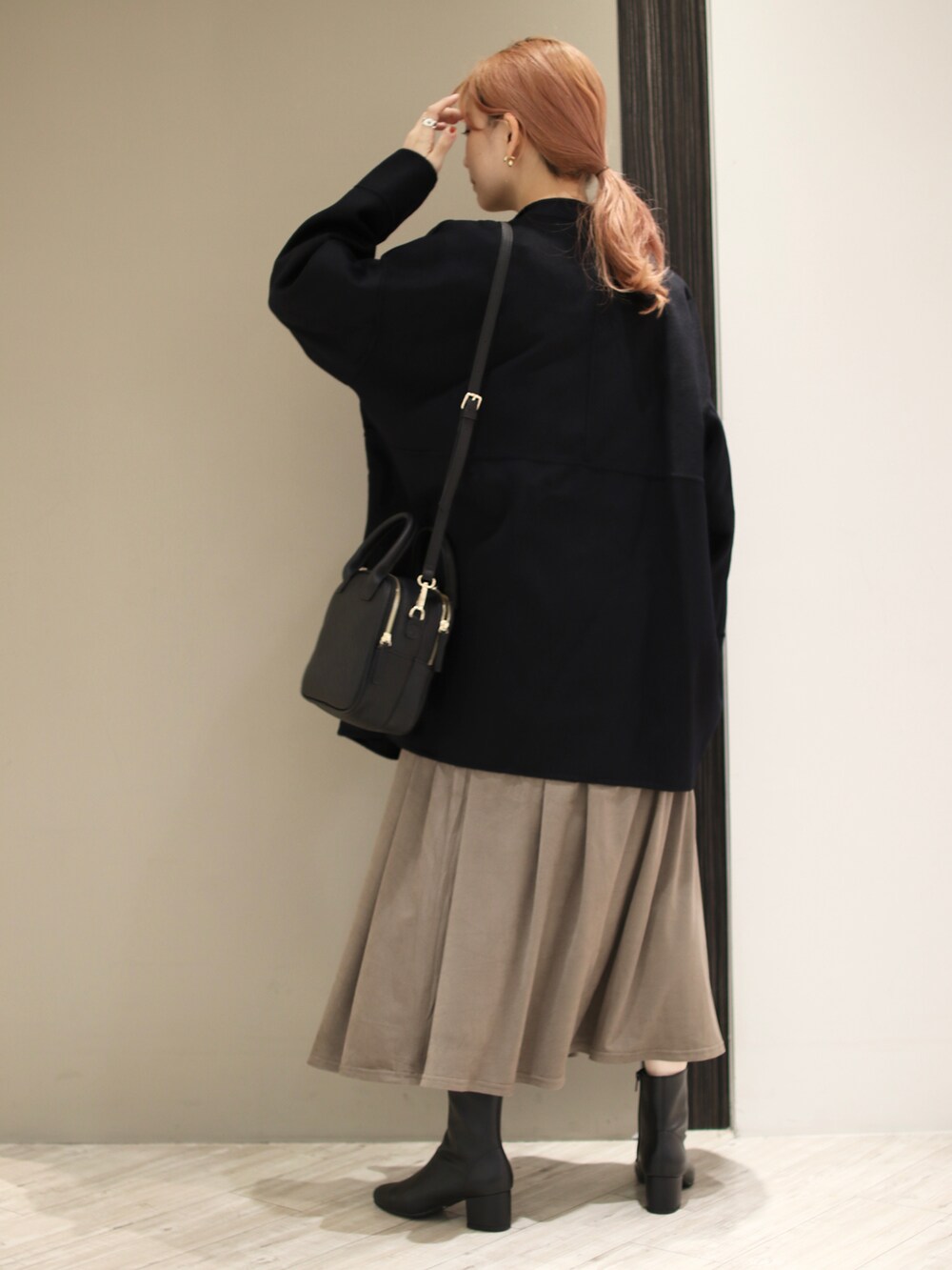 ブラウン系のスカート、ブラック系のブーツ、ブラック系のショルダーバッグを着用したレディースの冬コーディネートの3枚目の写真