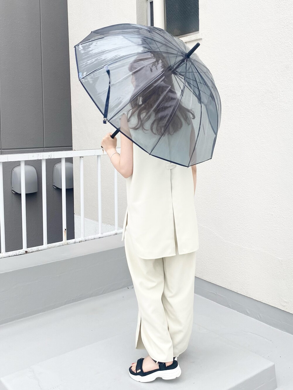 ブラック系のサンダル、ホワイト系のセットアップ、シルバー系のネックレスを着用したレディースの夏コーディネートの2枚目の写真