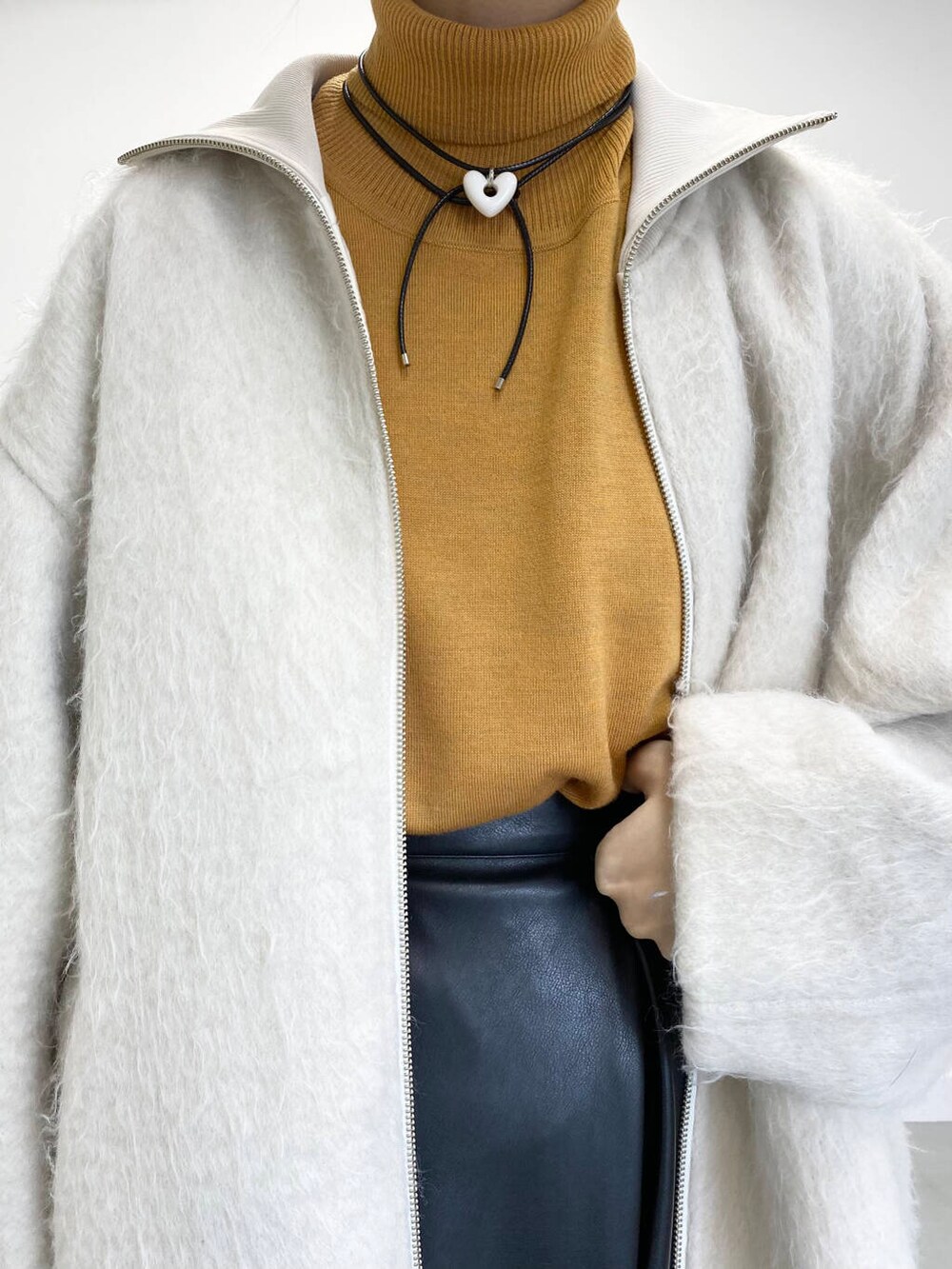 イエロー系のニット/セーター、ブラック系のショルダーバッグ、ブラック系のブーツを着用したレディースの冬コーディネートの10枚目の写真