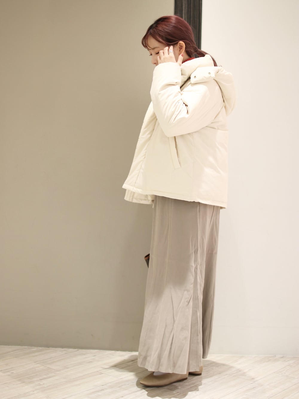 ホワイト系のダウンジャケット/コート、オレンジ系のニット/セーター、ベージュ系のスカートを着用したレディースの冬コーディネートの2枚目の写真