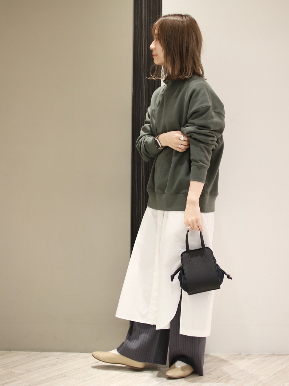ブラック系のショルダーバッグ、グリーン系のスウェット、ホワイト系のワンピースを着用したレディースの冬コーディネートの3枚目の写真