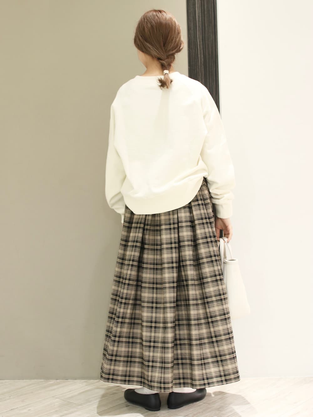 ベージュ系のスカート、ホワイト系のスウェット、ブラック系のパンプスを着用したレディースの冬コーディネートの3枚目の写真