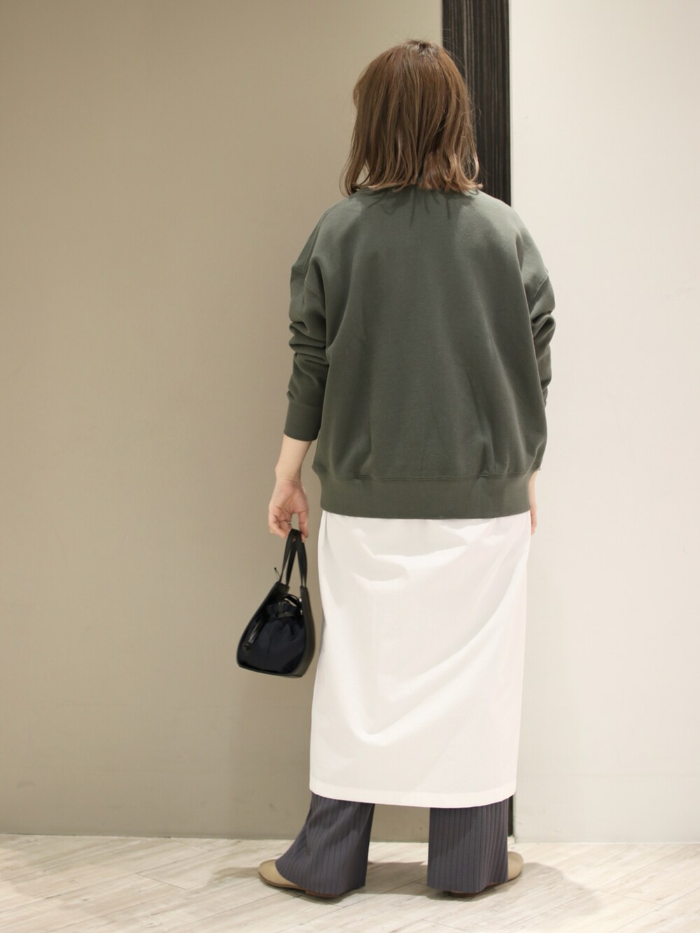 ブラック系のショルダーバッグ、グリーン系のスウェット、ホワイト系のワンピースを着用したレディースの冬コーディネートの2枚目の写真