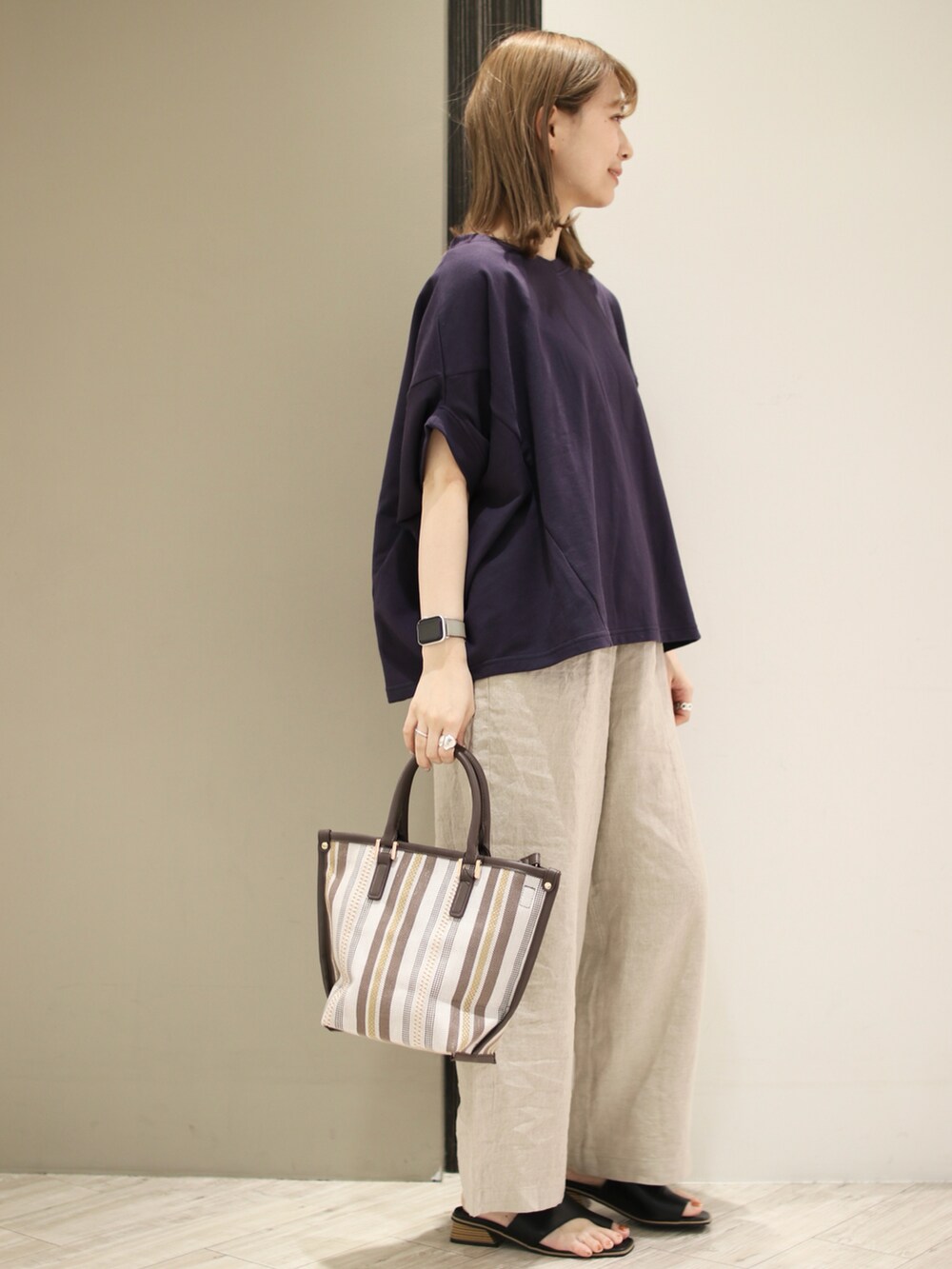 ブラウン系のトートバッグ、ベージュ系のその他パンツ、ブラック系のサンダルを着用したレディースの春コーディネートの3枚目の写真