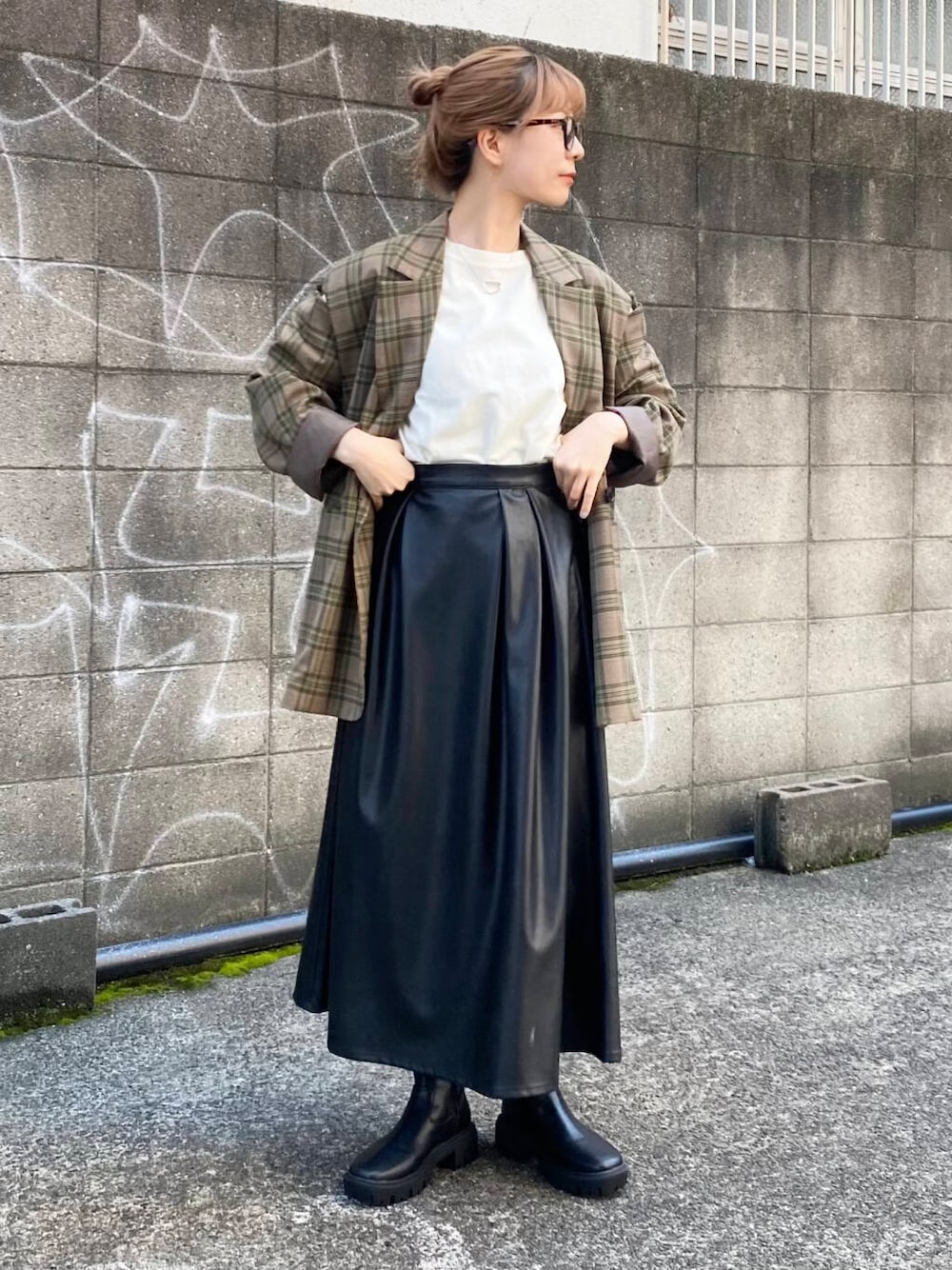グリーン系のテーラードジャケット、ブラック系のブーツ、ブラック系のスカートを着用したレディースの秋コーディネートの2枚目の写真