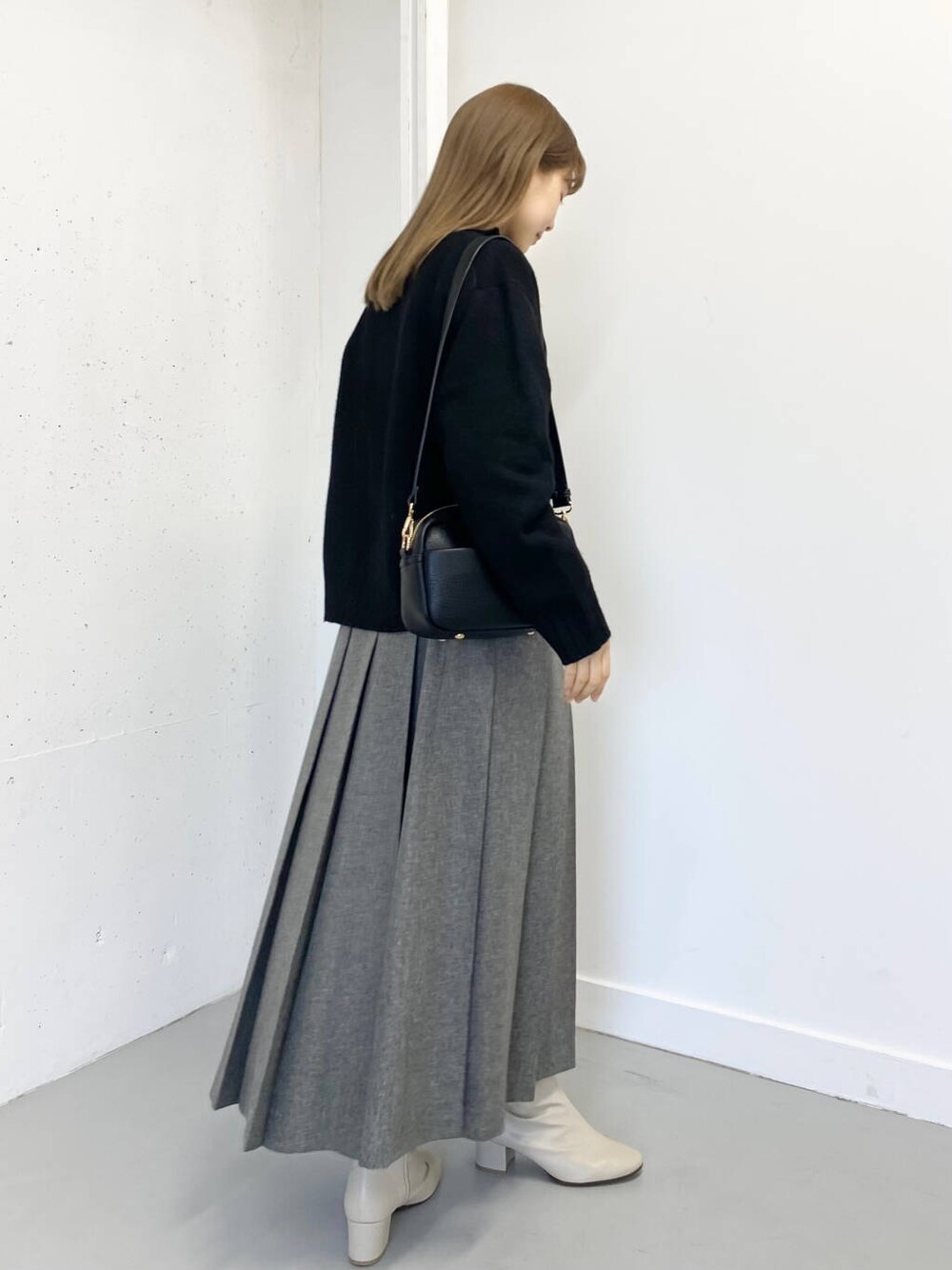 ホワイト系のブーツ、ブラック系のショルダーバッグ、グレー系のスカートを着用したレディースの冬コーディネートの3枚目の写真