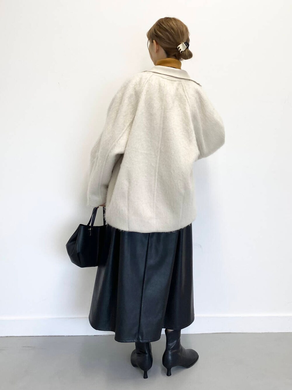 イエロー系のニット/セーター、ブラック系のショルダーバッグ、ブラック系のブーツを着用したレディースの冬コーディネートの9枚目の写真