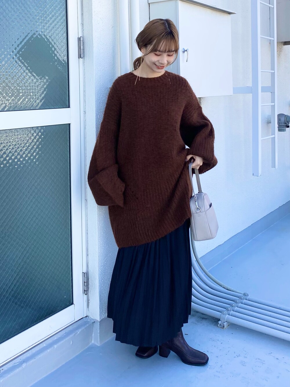 ベージュ系のショルダーバッグ、ブラウン系のブーツ、ブラック系のスカートを着用したレディースの冬コーディネートの3枚目の写真