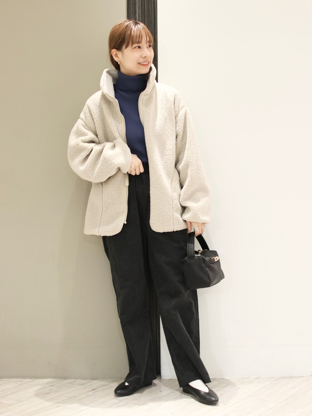 グレー系のその他パンツ、ブルー系のニット/セーター、ホワイト系のブルゾンを着用したレディースの冬コーディネートの2枚目の写真