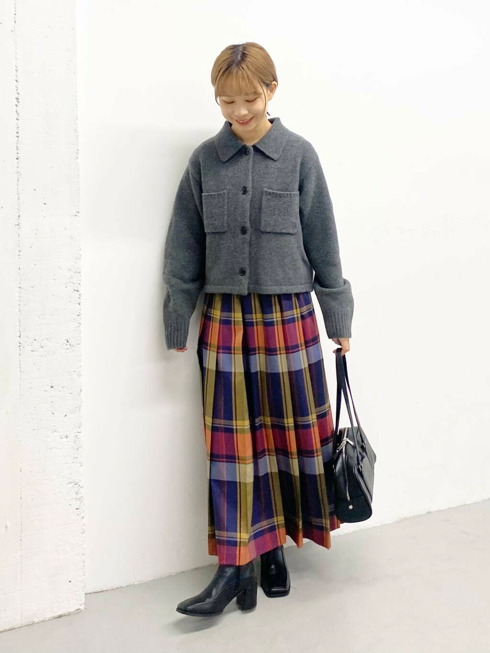 ブラック系のボストンバッグ、ブラック系のブーツ、ブルー系のスカートを着用したレディースの秋コーディネートの5枚目の写真