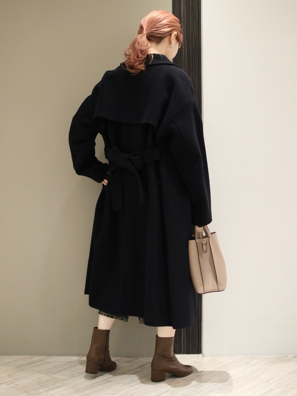 ブラウン系のトートバッグ、ブラック系のスカート、ホワイト系のニット/セーターを着用したレディースの冬コーディネートの3枚目の写真