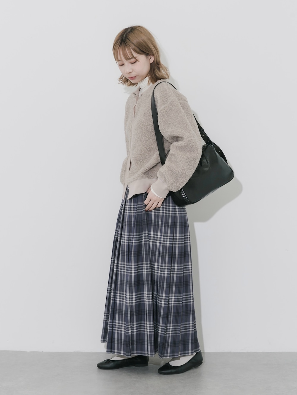 グレー系のスカート、ベージュ系のカーディガン/ボレロ、ブラック系のショルダーバッグを着用したレディースの秋コーディネートの5枚目の写真