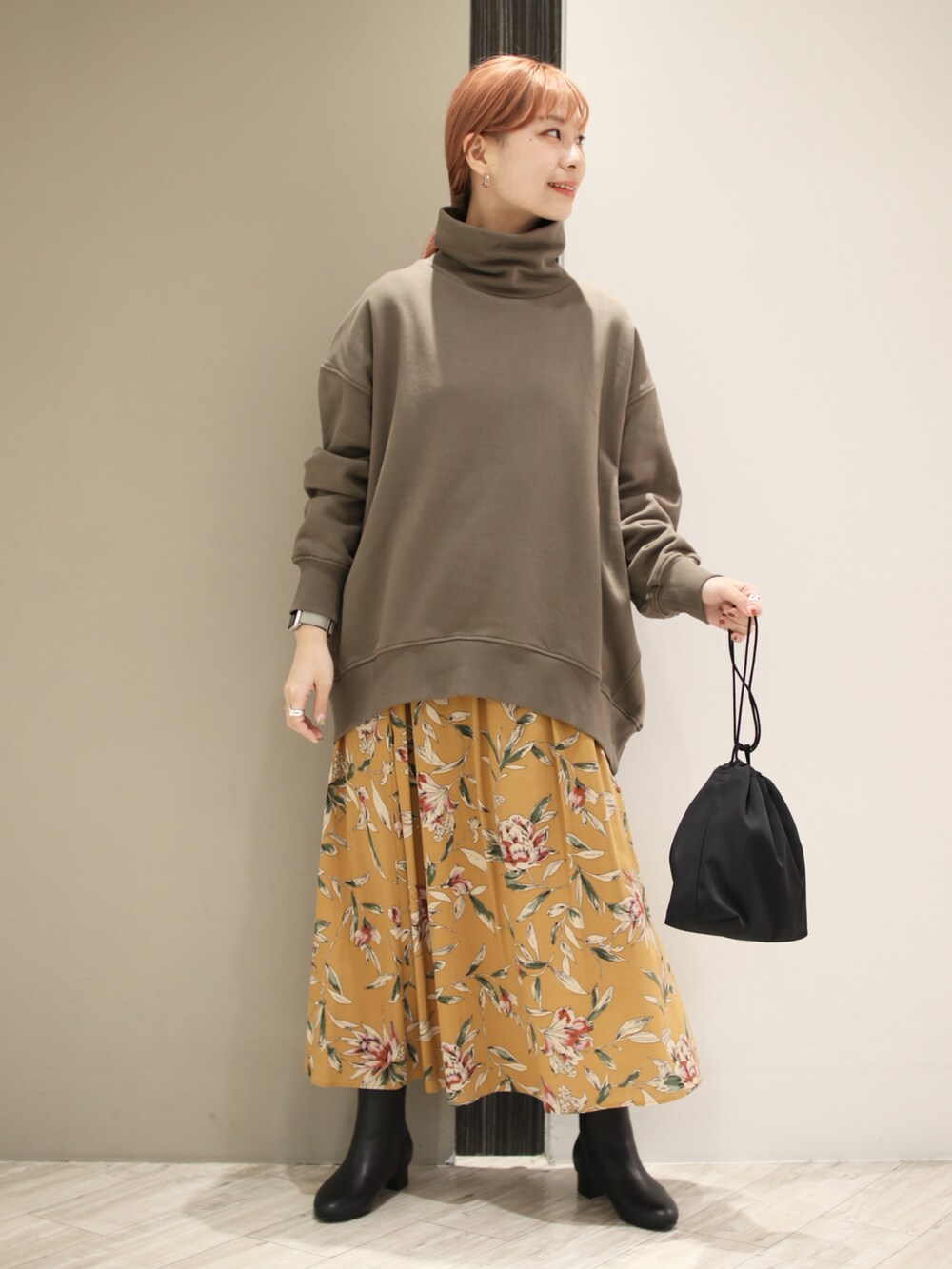 グリーン系のスウェット、オレンジ系のスカート、ブラック系のショルダーバッグを着用したレディースの秋コーディネートの3枚目の写真